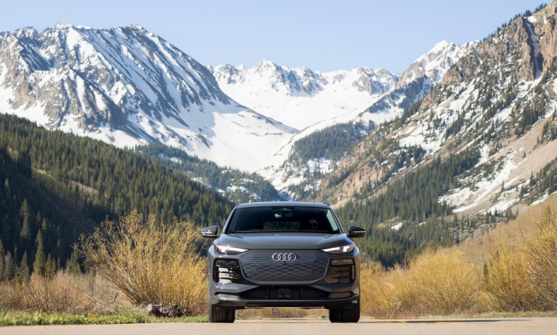 Gray Audi SUV direct front view on road with snow-capped mountains in the background.
