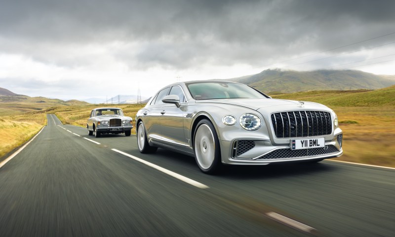 Bentley 1965 T Series and 2025 Flying Spur Azure at speed on a road in open country.