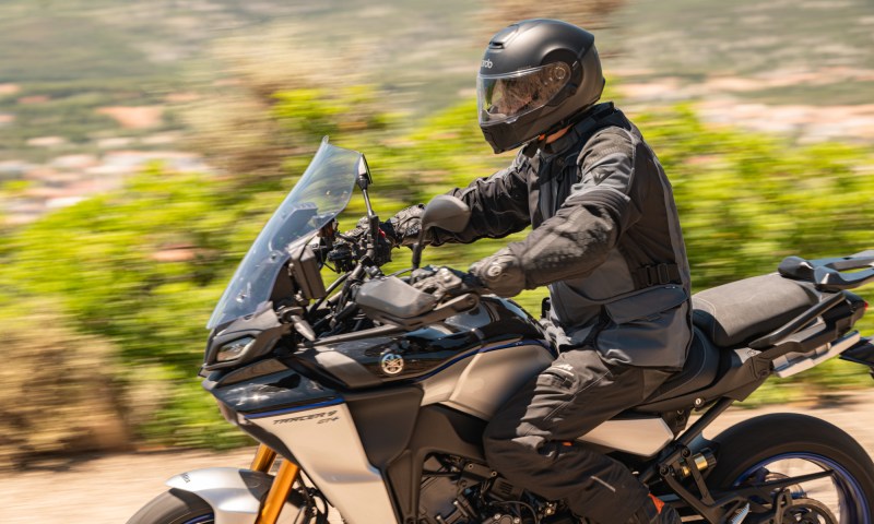 Rider on a motorcycle wearing a Cardo Beyond GTS smart helmet.